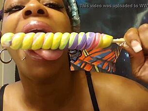 Ebony babe samples a unicorn lollipop in a fetish setting.