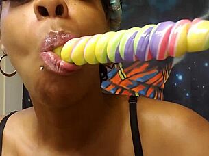 Ebony babe samples a unicorn lollipop in a fetish setting.