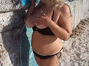 Look at that milf playing with her big tits and ass on the public beach!