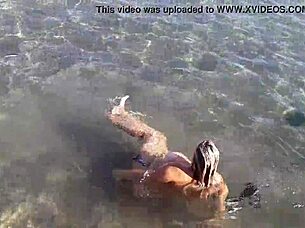 Look at that milf playing with her big tits and ass on the public beach!