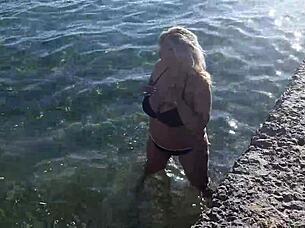 Look at that milf playing with her big tits and ass on the public beach!