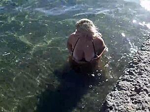 Look at that milf playing with her big tits and ass on the public beach!