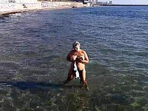 Look at that milf playing with her big tits and ass on the public beach!