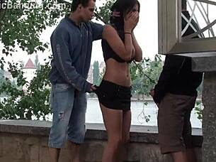 A busty teen encounters a group of guys in a public street setting for an outdoor activity