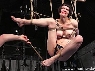 Tattooed slave Reversa in suspension bondage with caning and tit torture.