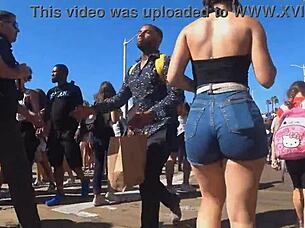 In a public outdoor setting, a voyeur captures a candid shot of a big ass in tight shorts and jeans.