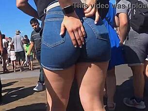In a public outdoor setting, a voyeur captures a candid shot of a big ass in tight shorts and jeans.