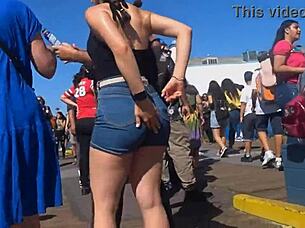 In a public outdoor setting, a voyeur captures a candid shot of a big ass in tight shorts and jeans.