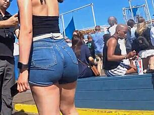 In a public outdoor setting, a voyeur captures a candid shot of a big ass in tight shorts and jeans.