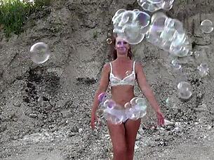 Mature amateur in see-through bikini plays with soap bubbles.