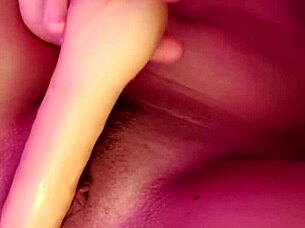 Curly-haired submissive lesbian in socks masturbates her natural tits and pussy with big dildo, achieving creamy cumshot