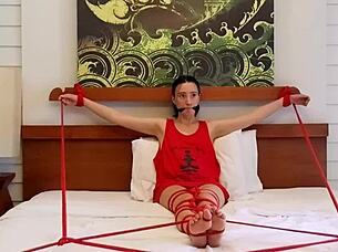 sofi finds herself bound with red ropes tightly on the soft bed in suspense
