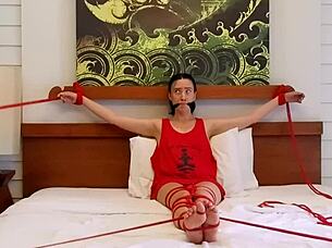 sofi finds herself bound with red ropes tightly on the soft bed in suspense