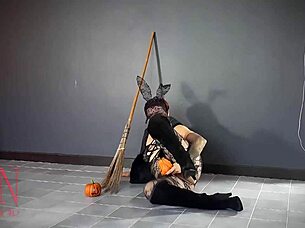 Halloween witch in pantyhose teases with pumpkins and broom in old house stairway performance