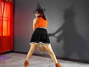 Halloween witch in pantyhose teases with pumpkins and broom in old house stairway performance