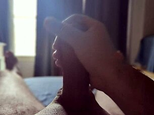 Solo guy masturbates his big cock with sun rays streaming through the bedroom window