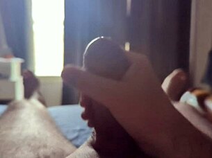 Solo guy masturbates his big cock with sun rays streaming through the bedroom window