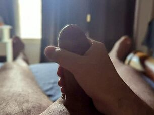 Solo guy masturbates his big cock with sun rays streaming through the bedroom window