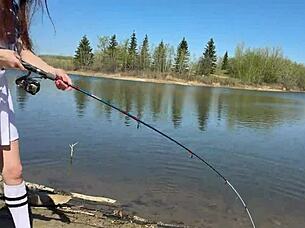 young petite girl in fishnets and skirt fishes outdoors after school