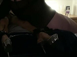 Two dominant figures engage in an activity involving a bound participant who receives a specific treatment.