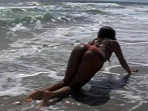 Ebony babe fucks dildo on public beach