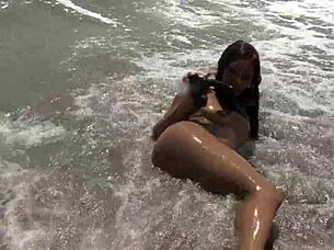 Ebony babe fucks dildo on public beach
