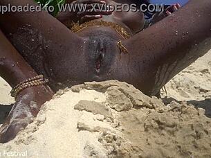 Skinny dark beauty teases outdoors in sand