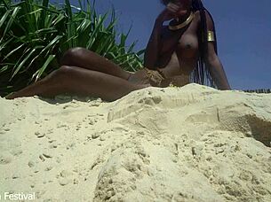 Skinny dark beauty teases outdoors in sand