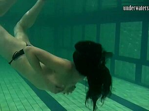 Brunette teen swims naked in pool, tight pussy exposed.