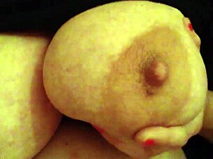 A woman handles her large breasts while working in the office