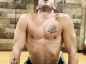 muscular bodybuilder stretching his sexy muscles in the gym